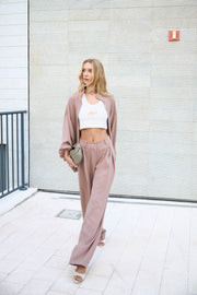 Woman in a pink outfit standing against a light-colored wall.